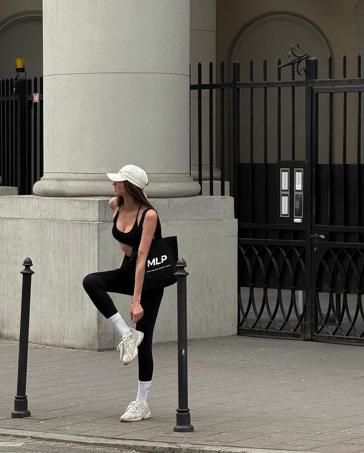 Une personne souriante, portant des lunettes et un t-shirt, regarde vers le bas tout en tenant et en utilisant un smartphone.