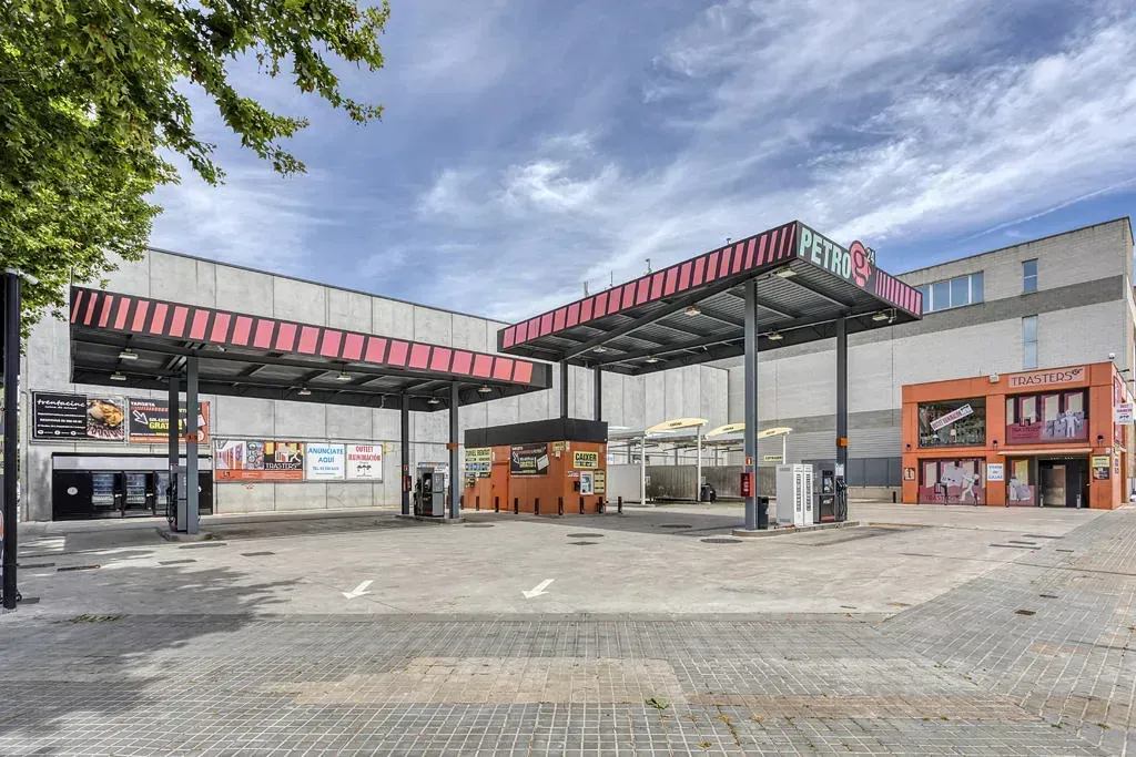 Entrada de cine con toldos rosas y rojos, carteles de películas y un cielo nublado.