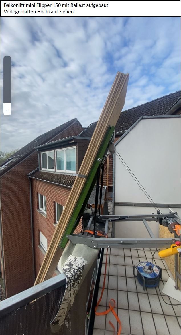 Bauarbeiten an der Gebäudeaußenseite: Holzpaneele lehnen an der Struktur; Gerüst auf dem Balkon; blauer Himmel.