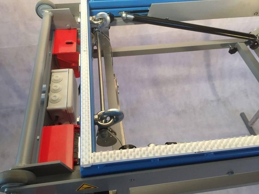 Nahaufnahme von Industriemaschinen. Grauer Rahmen mit roten Steuerkästen, Metallarm und Rädern.