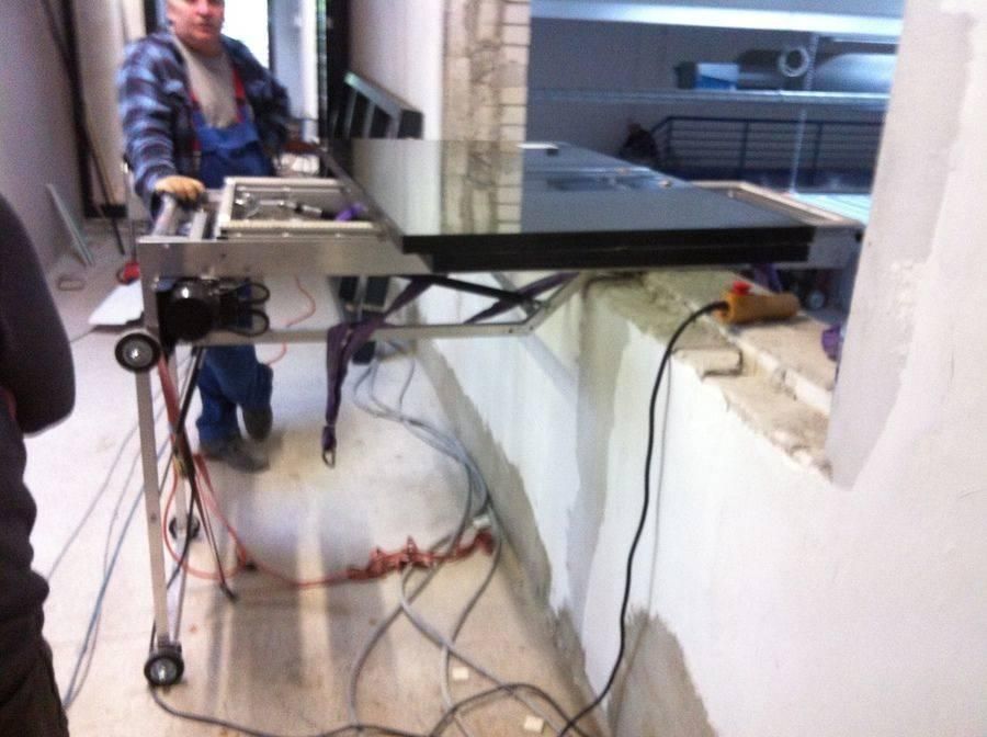 Mann installiert eine schwarze Arbeitsplatte, unterstützt von einem mobilen Lift, in der Nähe einer Fensteröffnung.