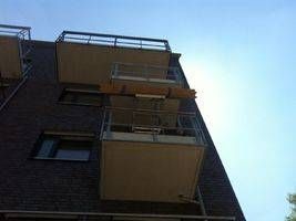 Balkone an einem dunklen Backsteingebäude mit Blick auf den klaren blauen Himmel.