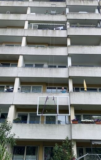 Eine große Fensterscheibe wird in ein Hochhaus gehoben.