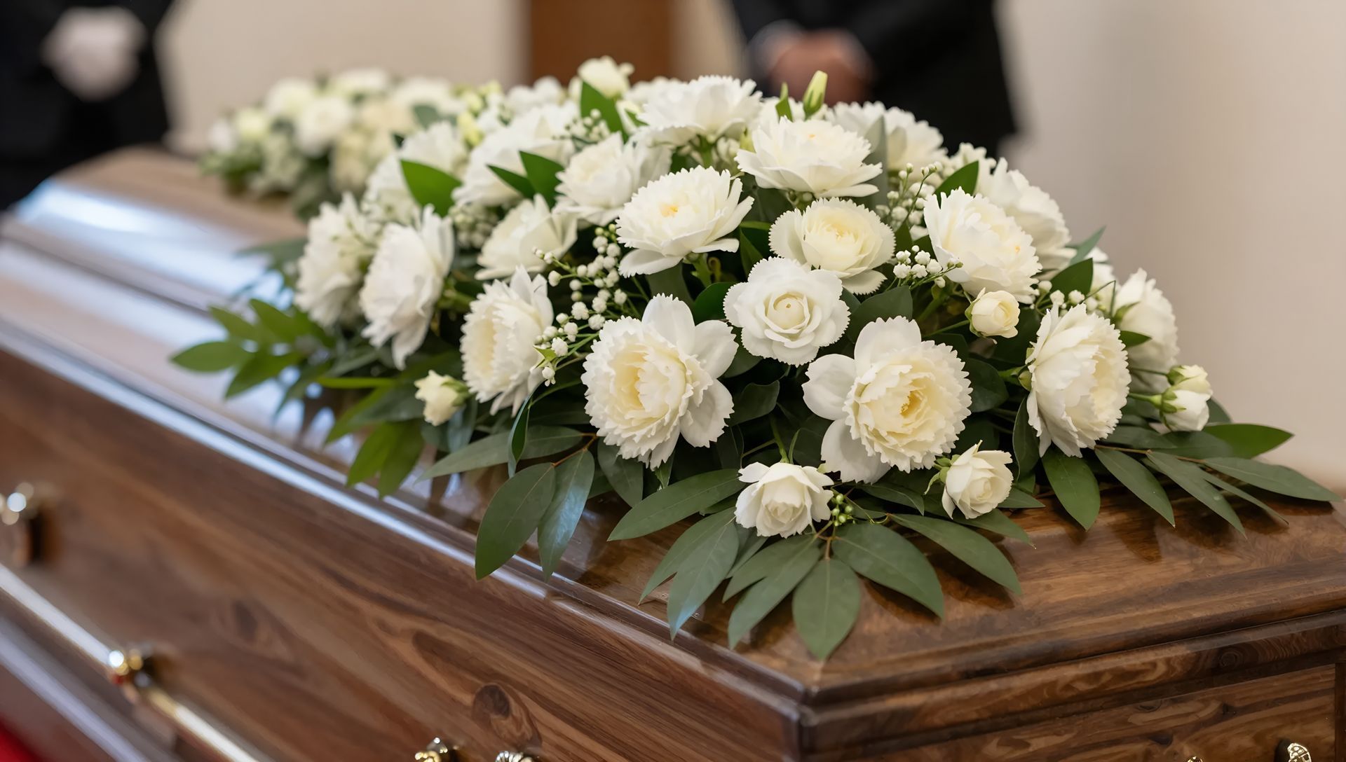 Composition florale blanche sur un cercueil en bois poli lors d'un service funéraire