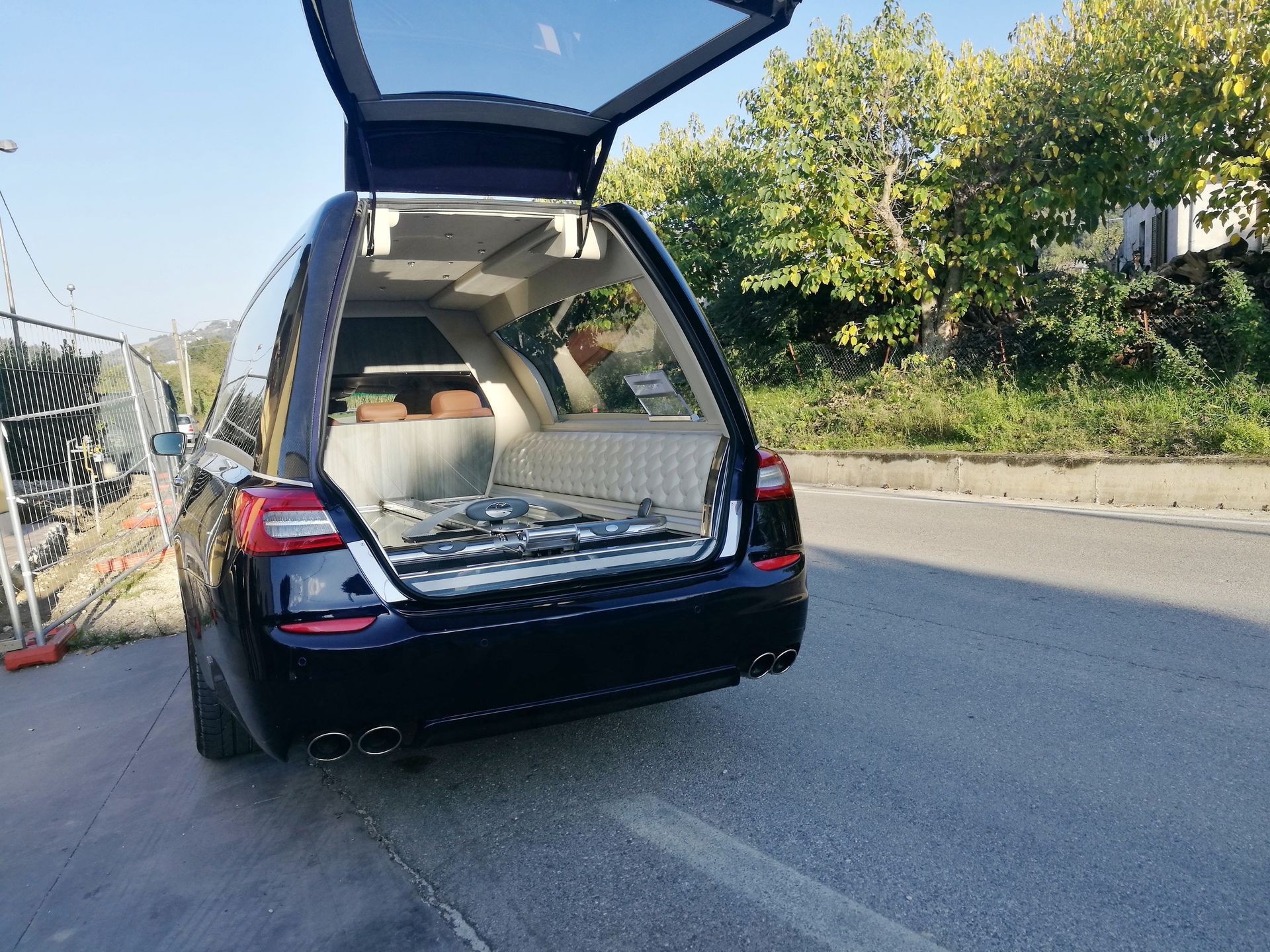 Un SUV noir est stationné sur une route, son hayon arrière ouvert, laissant apparaître un coffre chargé.