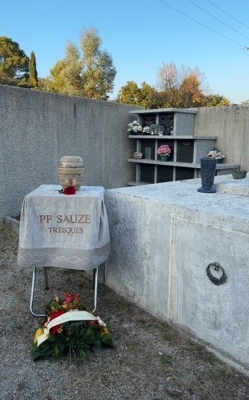 Les personnes en deuil se sont rassemblées autour d'un cercueil recouvert de fleurs blanches lors d'une cérémonie funéraire en plein air.
