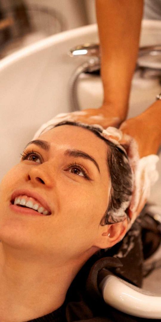 Una mujer se lava el cabello en un lavabo de una peluquería.