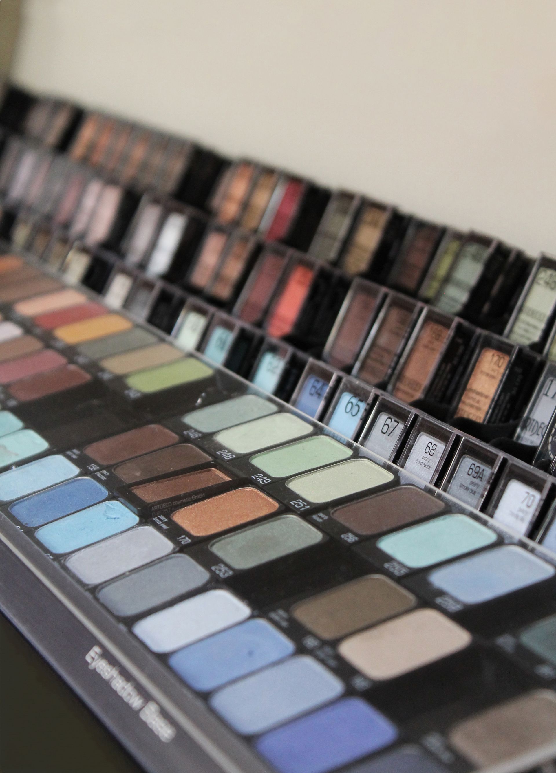 Una paleta de sombras de ojos, pinceles y tijeras sobre una mesa.