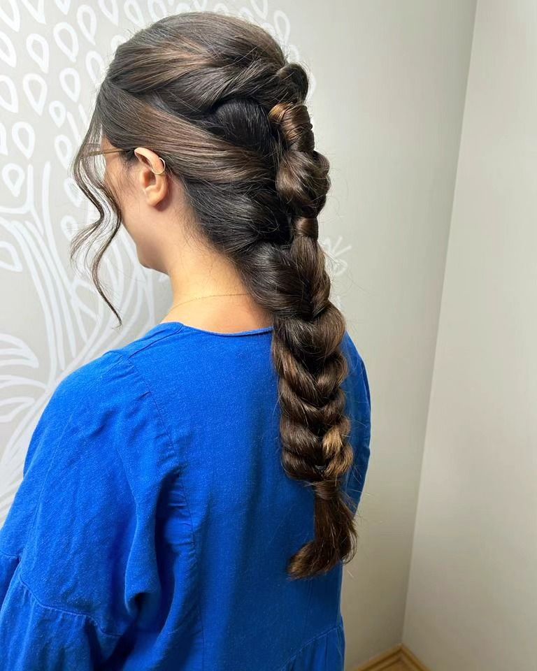 Mujer de cabello oscuro con peinado trenzado y vestida con una camisa azul.