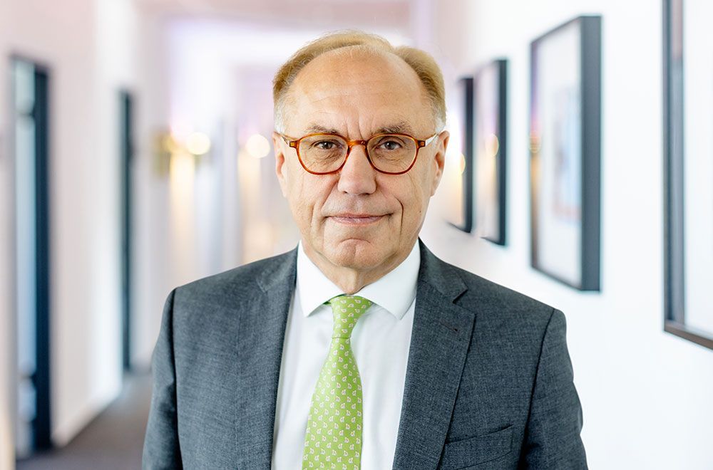 Ein Mann in Anzug und Krawatte sitzt mit zwei Frauen an einem Tisch.