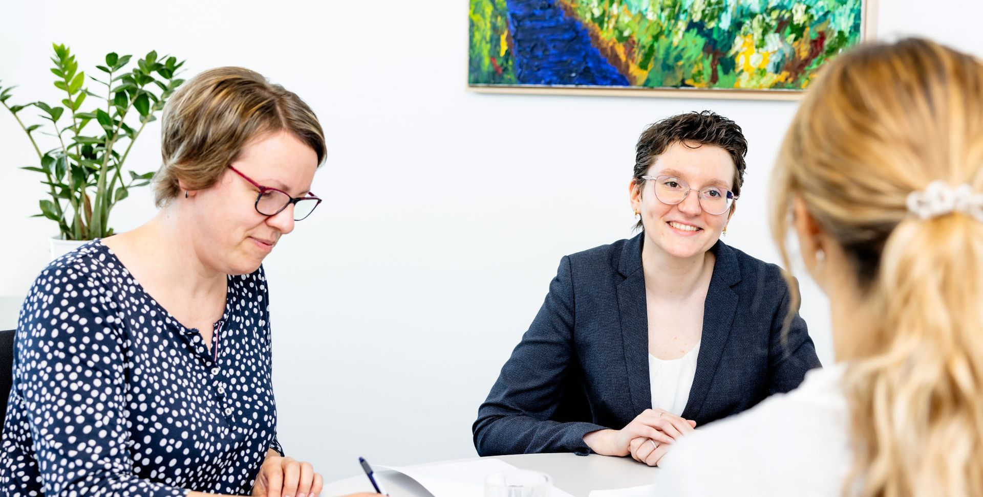 Drei Frauen sitzen an einem Tisch und unterhalten sich.