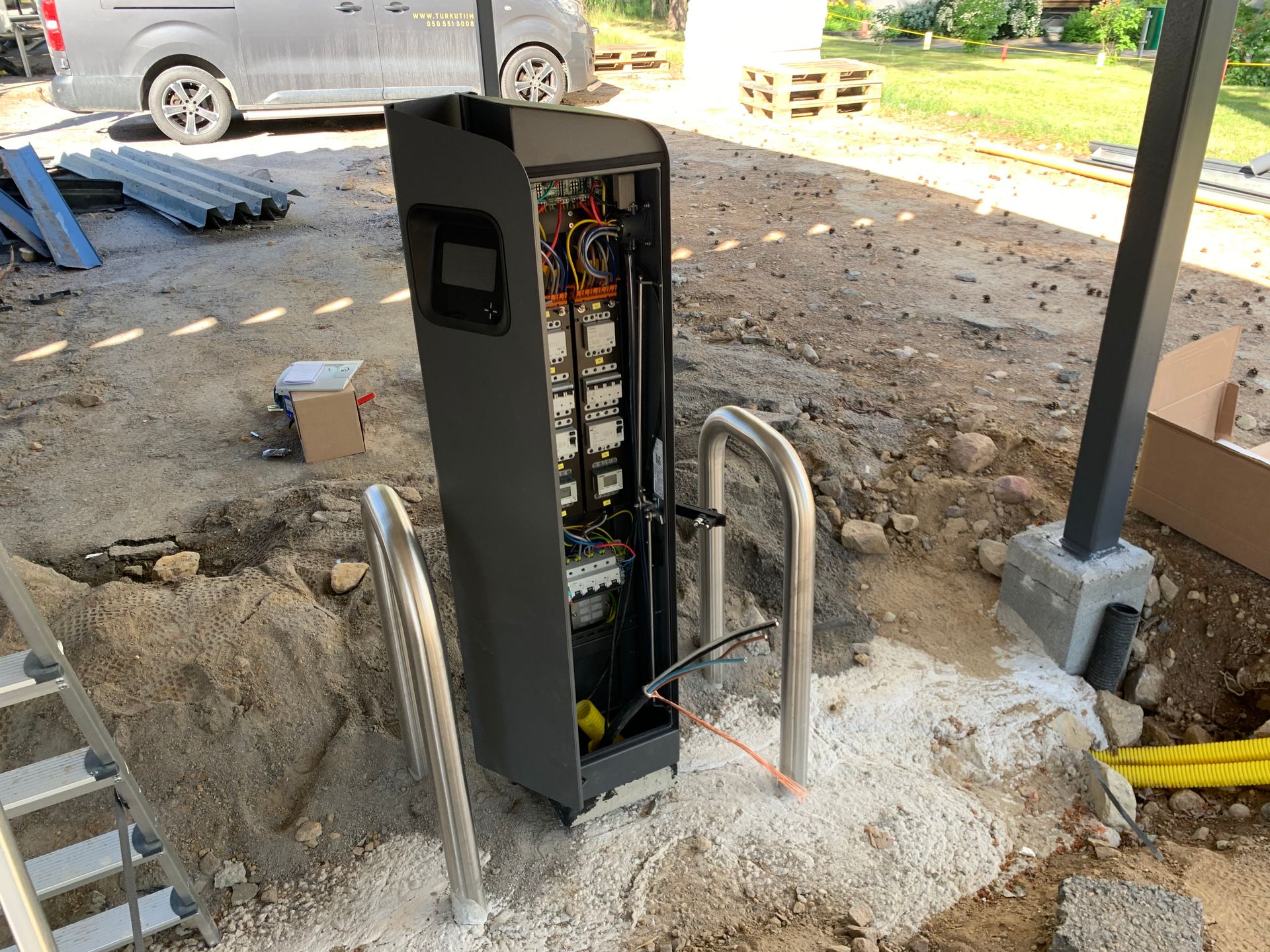 Rakennustelineiden kävelytie betonisen esteen ja rakennustyömaan vieressä, taustalla puita.