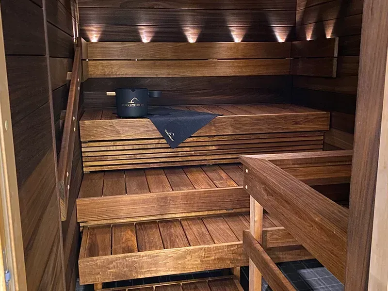 Tunnelmallinen valaistus ja lämpökäsitelty haapalaude modernissa turkulaisessa saunassa.