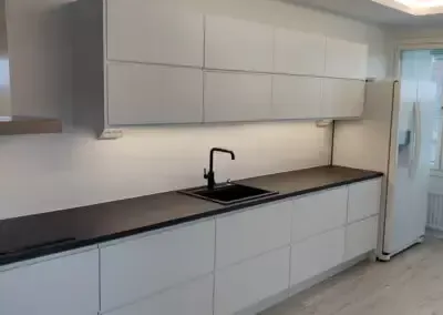 Keittiösaareke ja tyylikäs valaistus asennettuna osana laajempaa huoneistoremonttia.