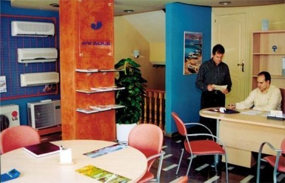 Dos hombres están de pie en una habitación con una exhibición de aires acondicionados.