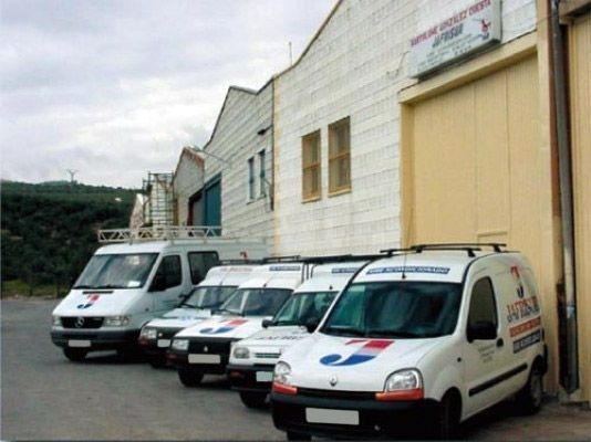 Una fila de furgonetas blancas están estacionadas frente a un edificio