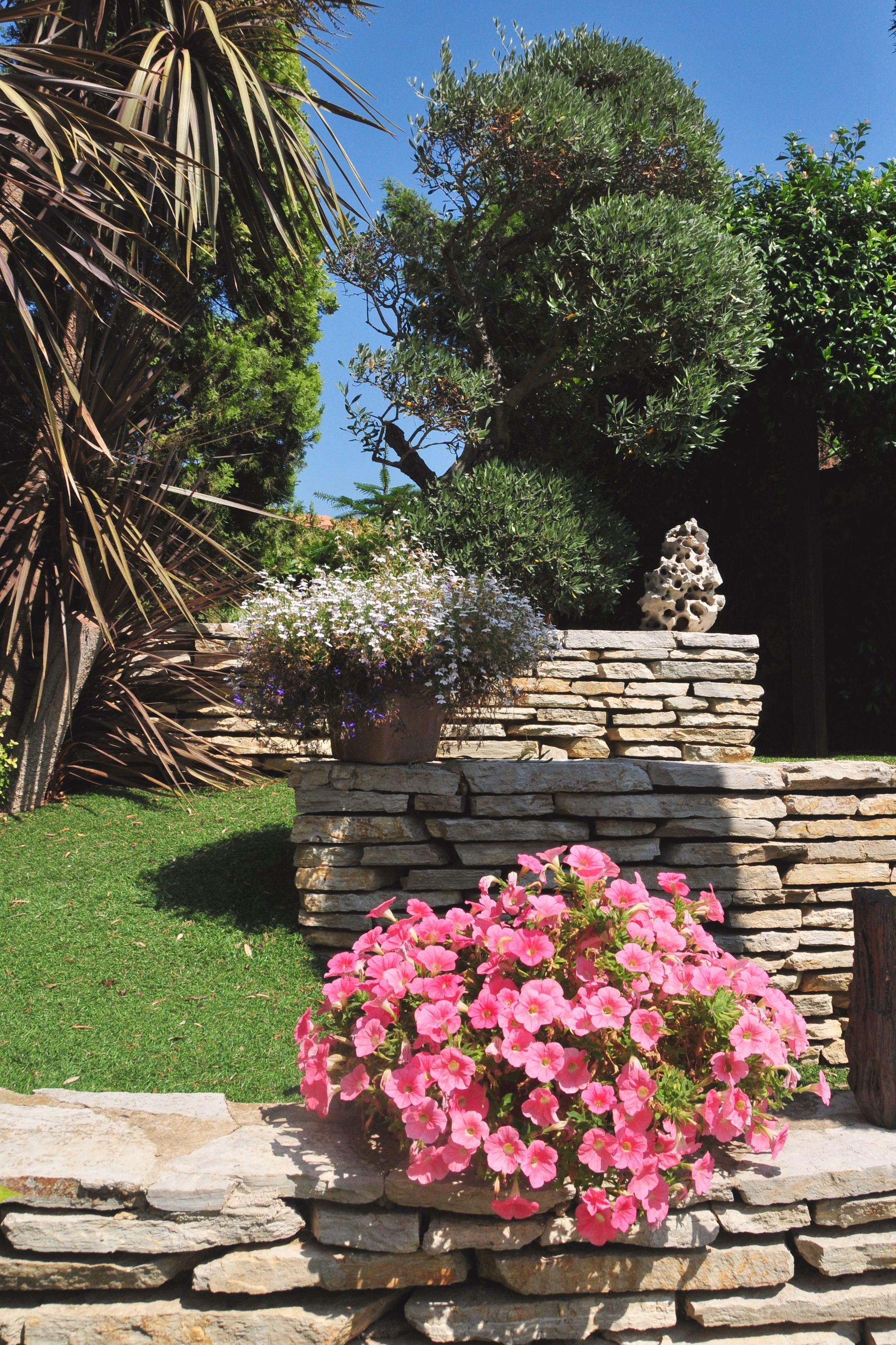 Jardin parfaitement entretenu avec fleurs et maçonnerie extérieure.