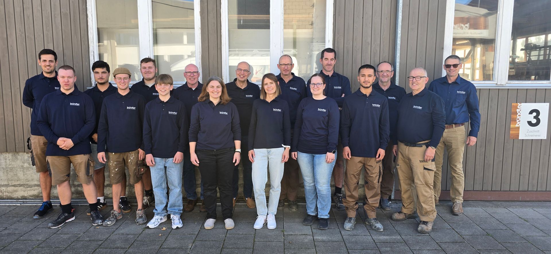 Eine Gruppe von Menschen posiert vor zwei Lieferwagen für ein Foto.