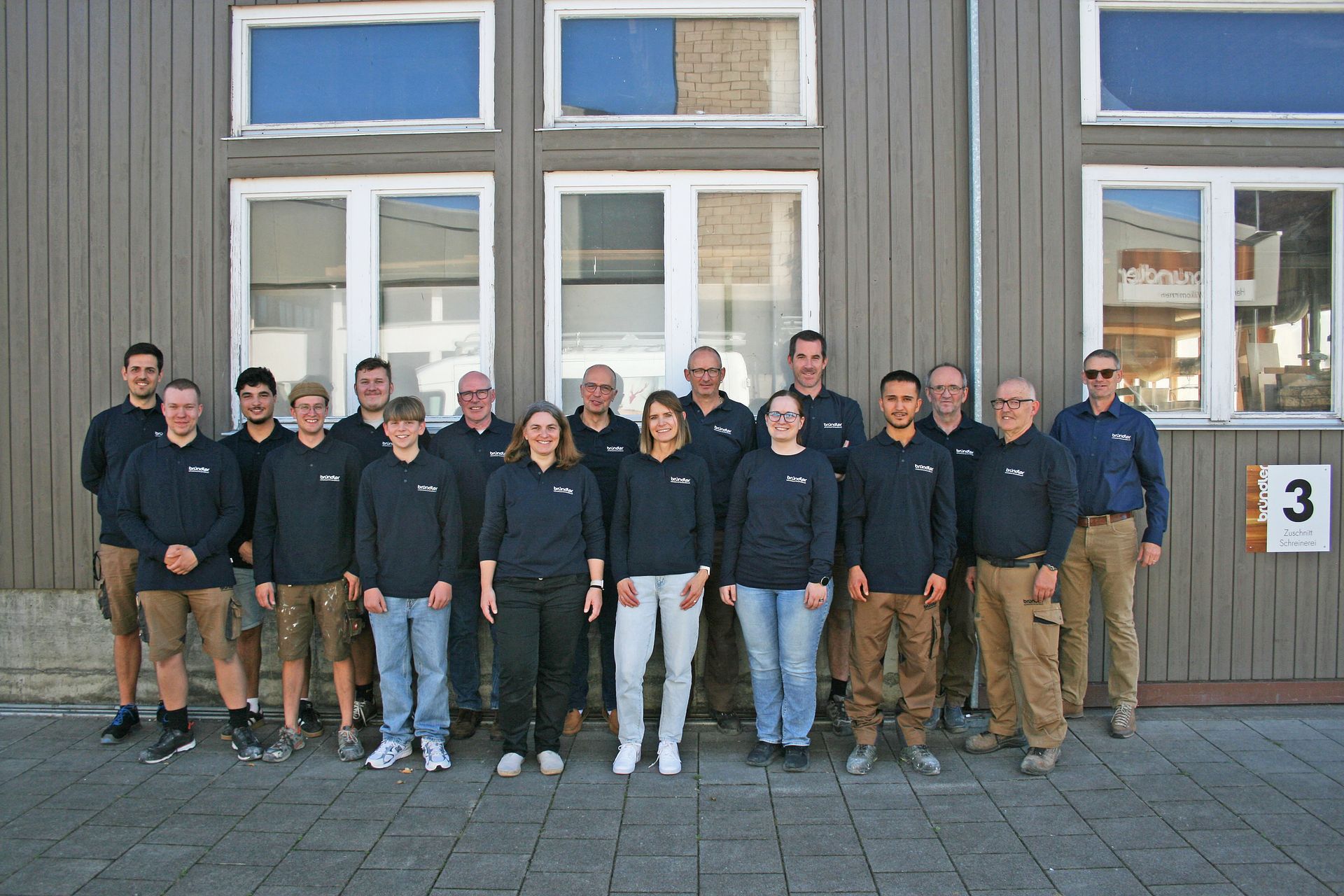 Eine Gruppe von Menschen posiert vor zwei Lieferwagen für ein Foto.