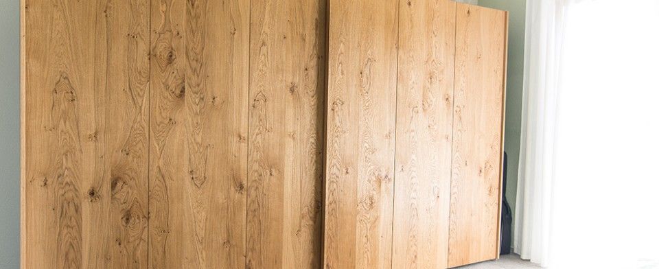 Ein grosser Holzkleiderschrank mit Schiebetüren in einem Schlafzimmer.