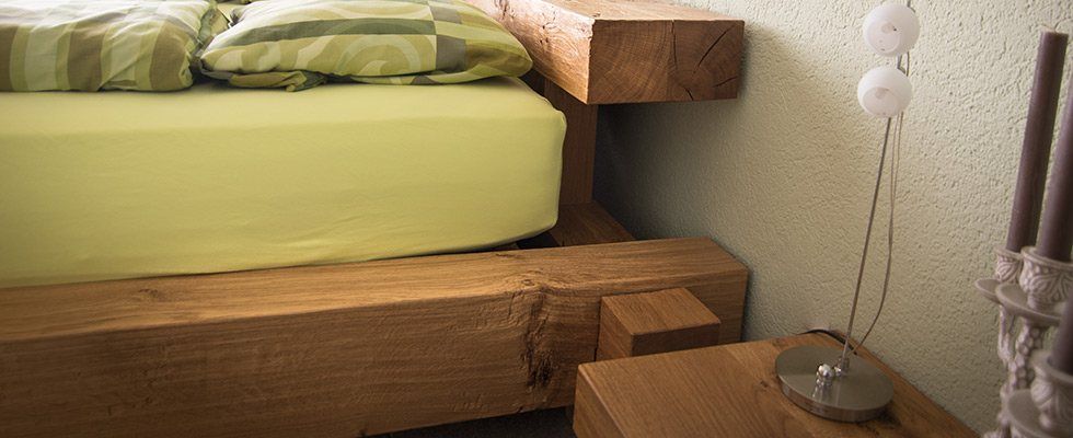 Ein Bett mit Holzrahmen und einem Nachttisch daneben.