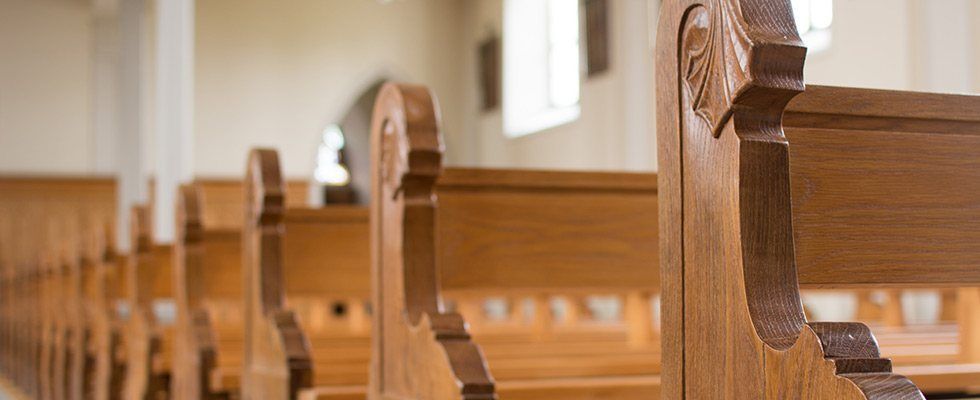 Eine Reihe Holzbänke in einer Kirche.