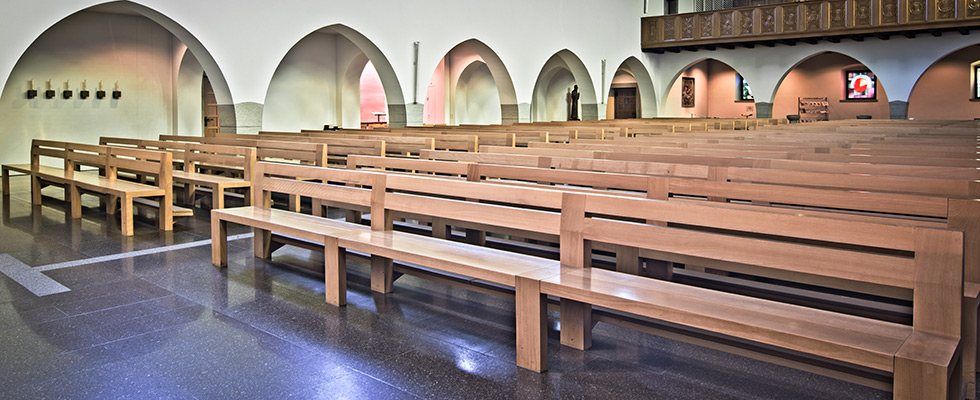 Eine Reihe Holzbänke in einer Kirche.