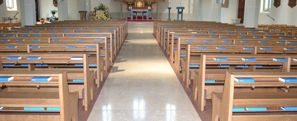 Reihen von Holzbänken in einer Kirche mit blauen Kissen