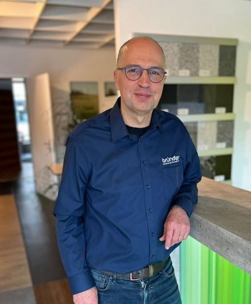 Ein Mann mit Brille und weißem Hemd lächelt in die Kamera.
