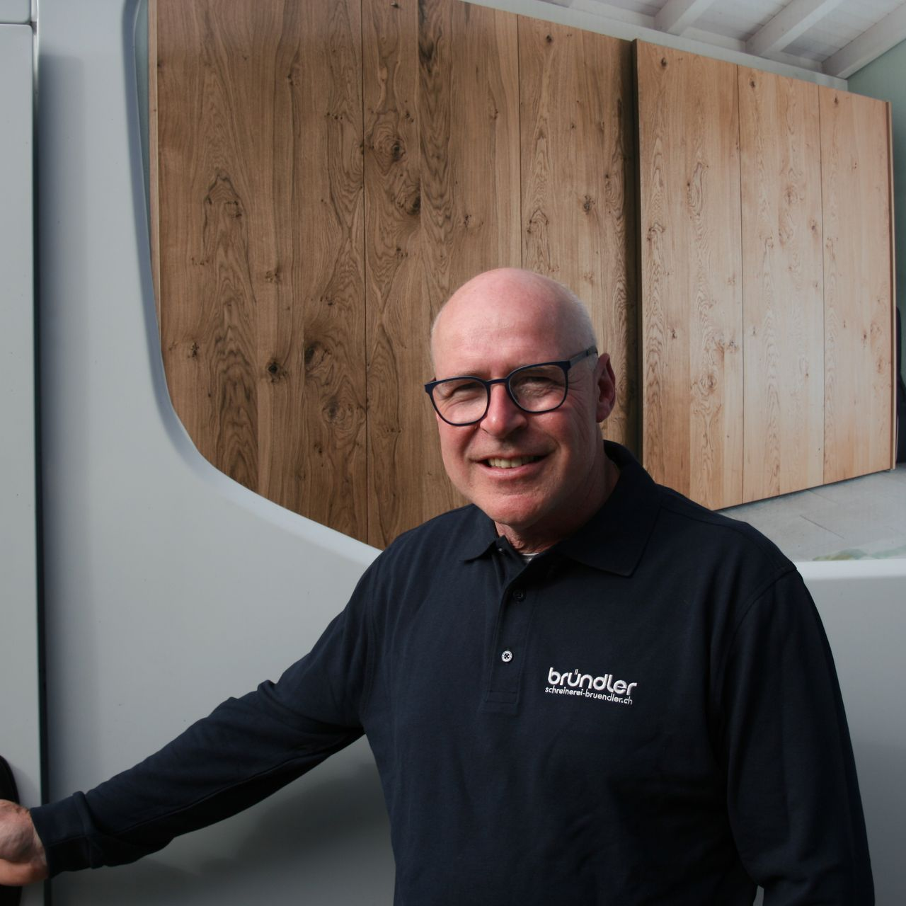 Ein Mann mit Hut und Brille lehnt an einem Tisch