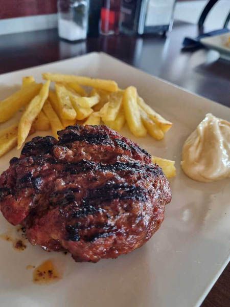 Un plato blanco cubierto con una hamburguesa y papas fritas