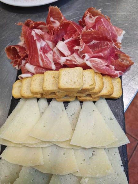 Una bandeja de carne y queso con galletas encima.