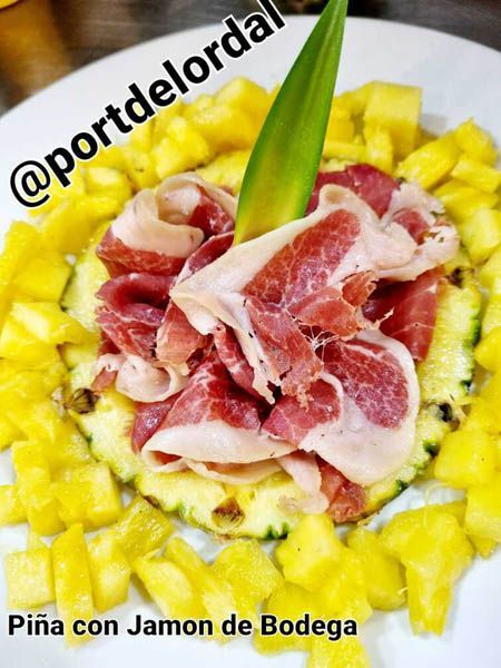 Un plato blanco cubierto con carne y rodajas de piña.