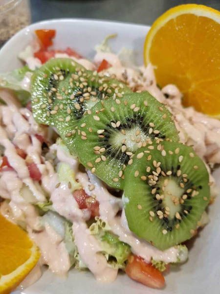 Una ensalada con rodajas de kiwi y semillas de sésamo encima.