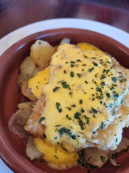 Un primer plano de un plato de comida con queso y patatas.