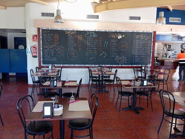 Un restaurante con mesas y sillas y un menú en la pared.