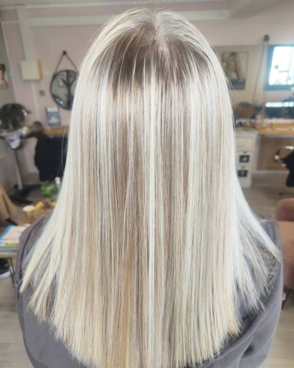 Cheveux blonds raides, mi-longs, avec des racines foncées, dans un salon de coiffure