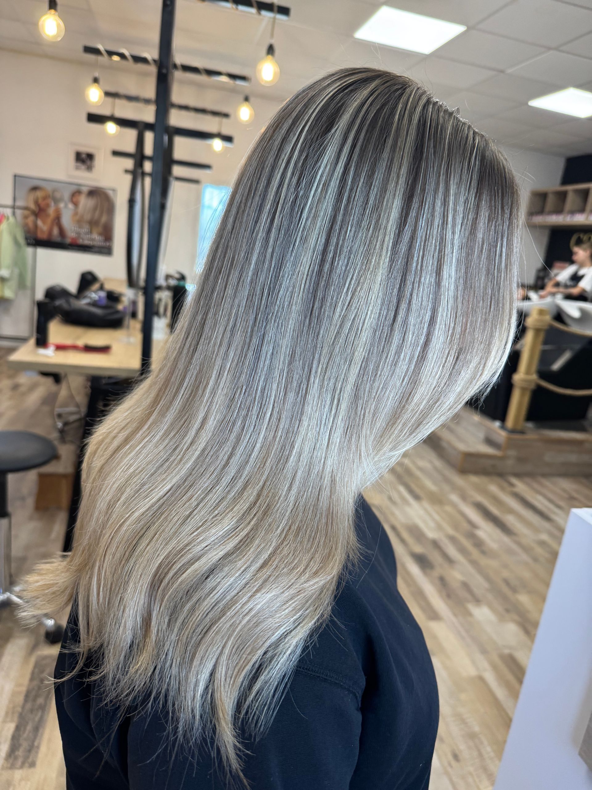 Vue de profil de cheveux blond argenté mi-longs avec des racines foncées dans un salon de coiffure