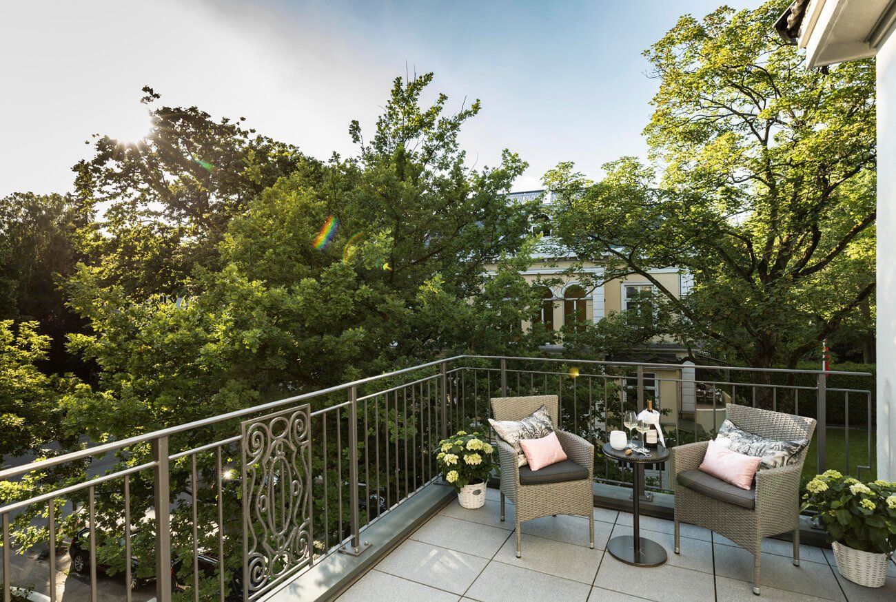 Ein Balkon mit zwei Stühlen und einem Tisch mit Bäumen im Hintergrund.