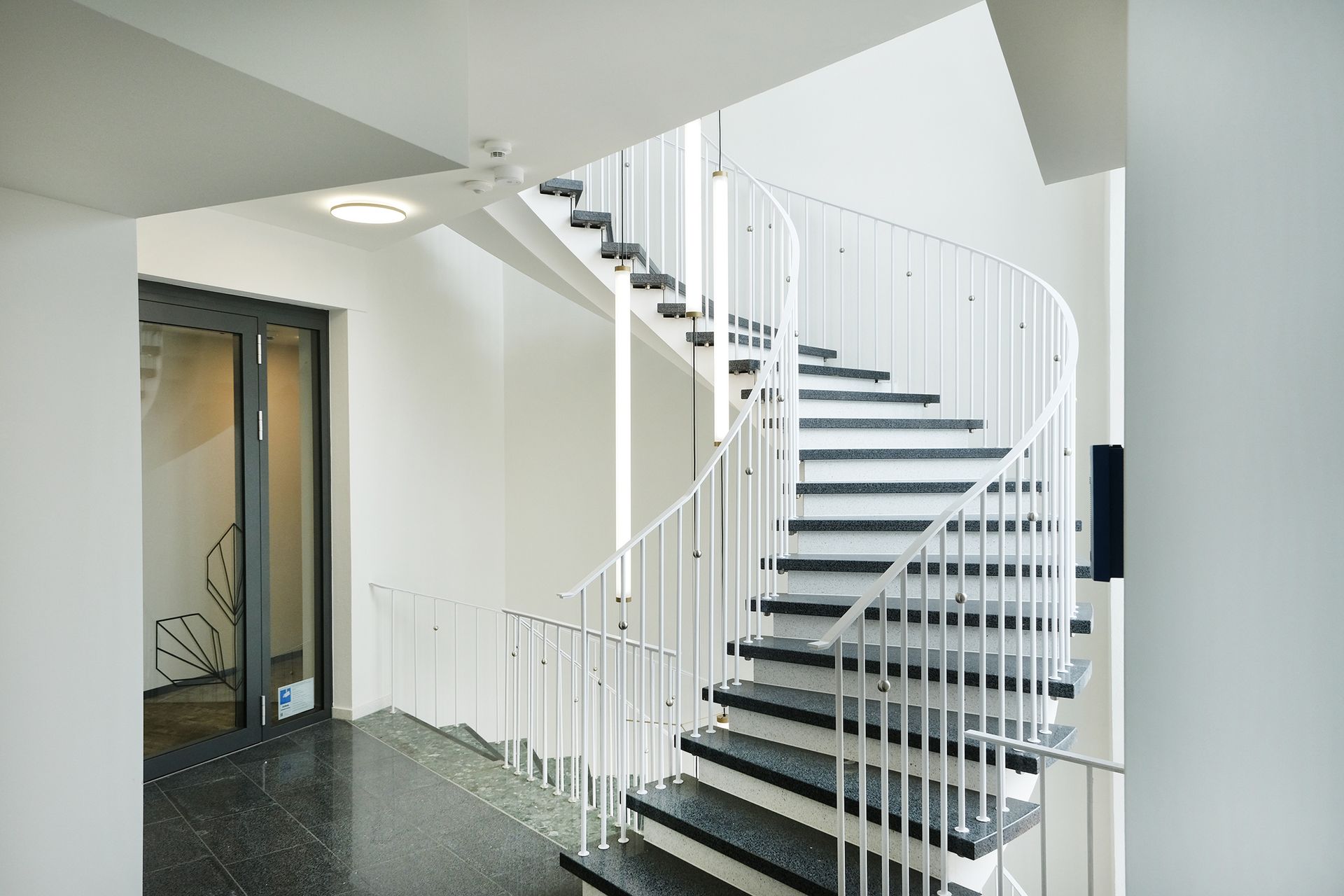 Eine Wendeltreppe mit schwarzen Stufen und einem weißen Geländer