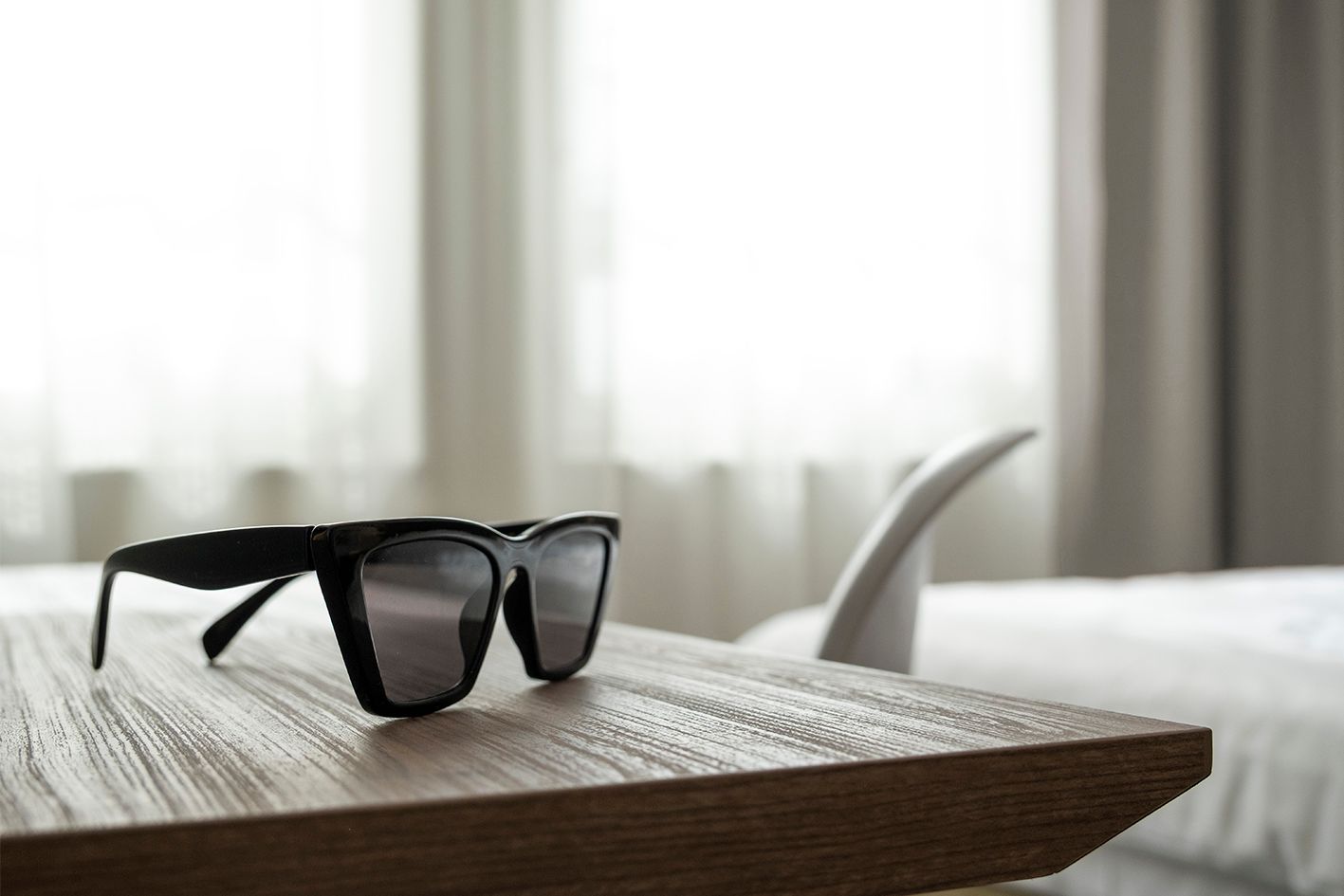 Eine Sonnenbrille liegt auf einem Holztisch.