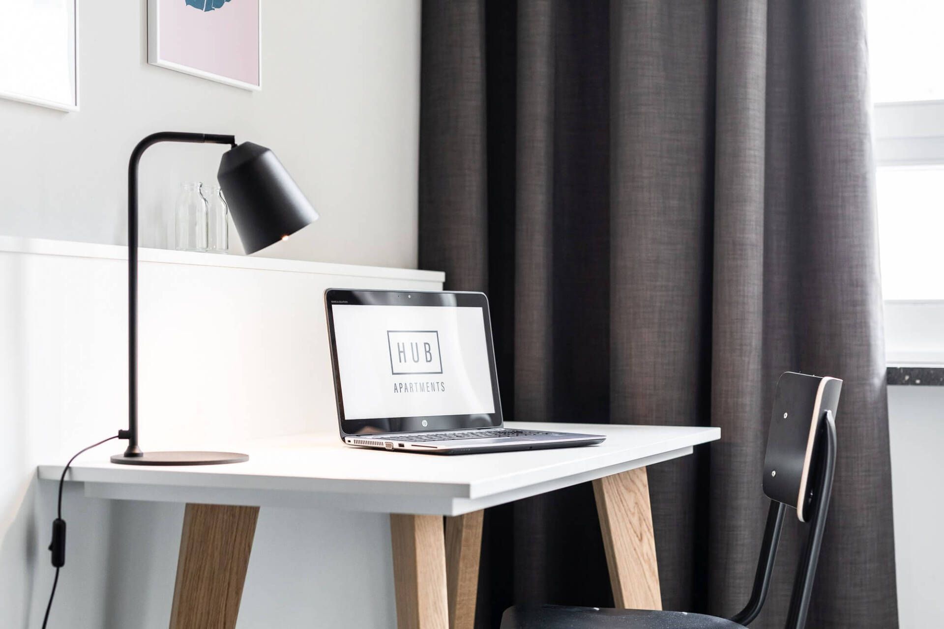 Ein Laptop steht auf einem Schreibtisch neben einer Lampe.