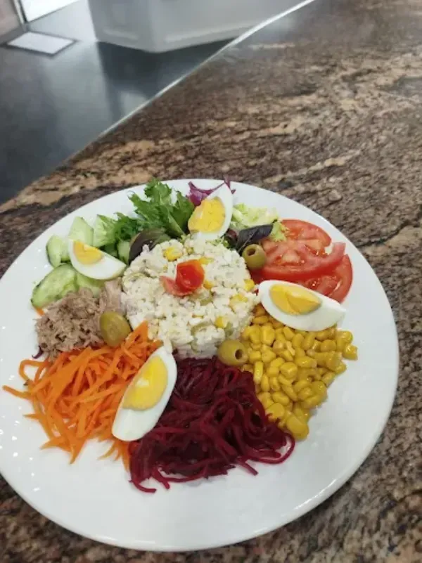 Un plato de ensalada colorido con una porción de arroz en el centro, rodeada de verduras frescas.