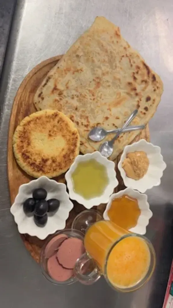 Una bandeja de madera con pan plano Msemen, una pequeña tortita redonda, aceitunas, miel, aceite, margarina, carne en rodajas