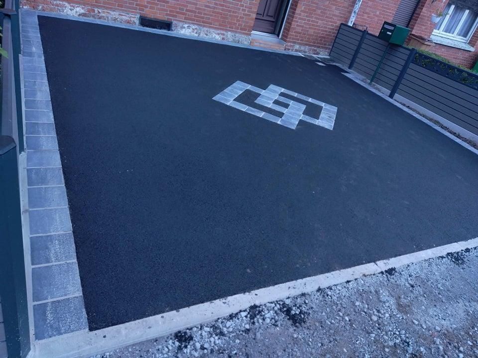 Allée en asphalte avec bordure en pierre grise et motif géométrique décoratif en pierre grise.