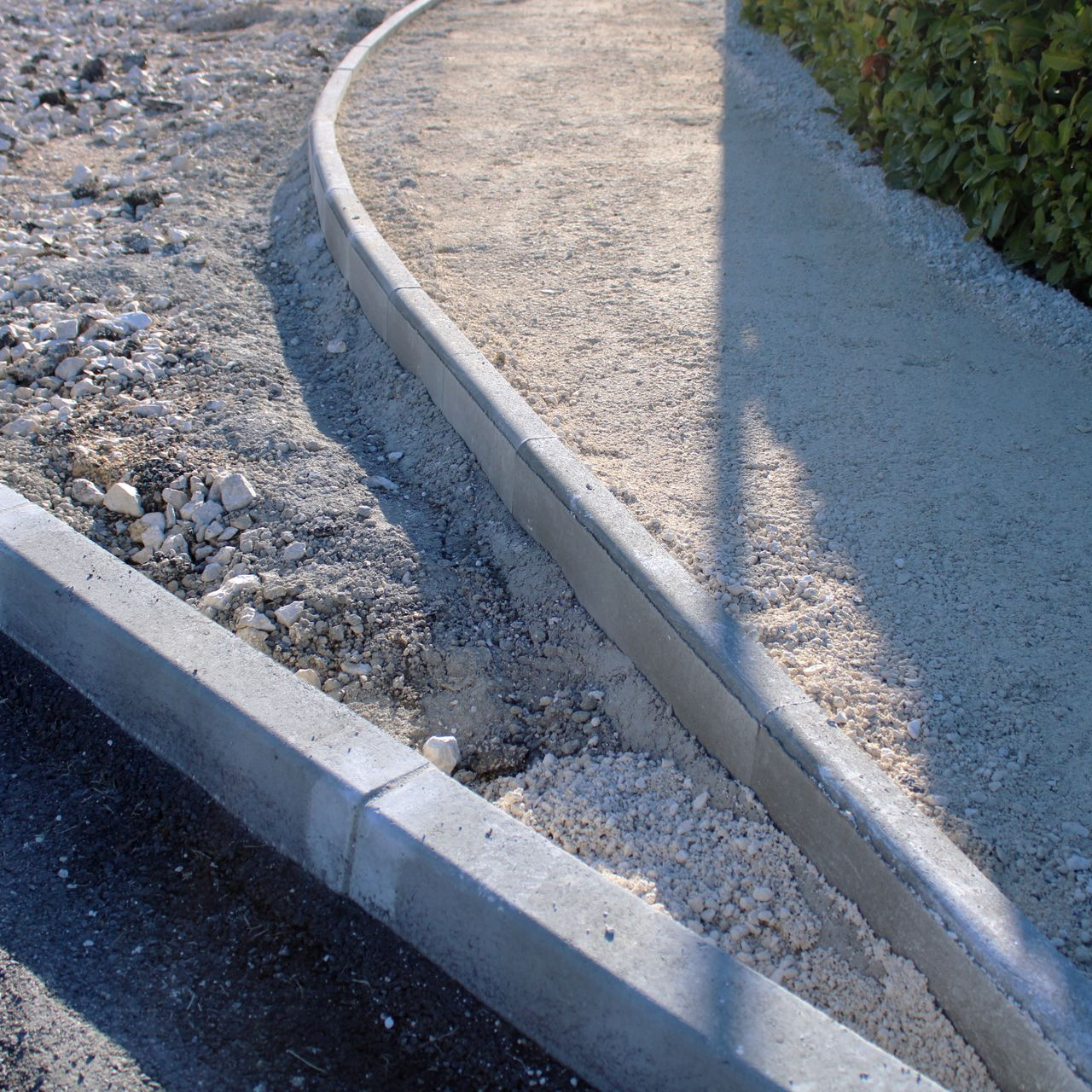 Chemin de gravier incurvé bordé de bordures en béton.