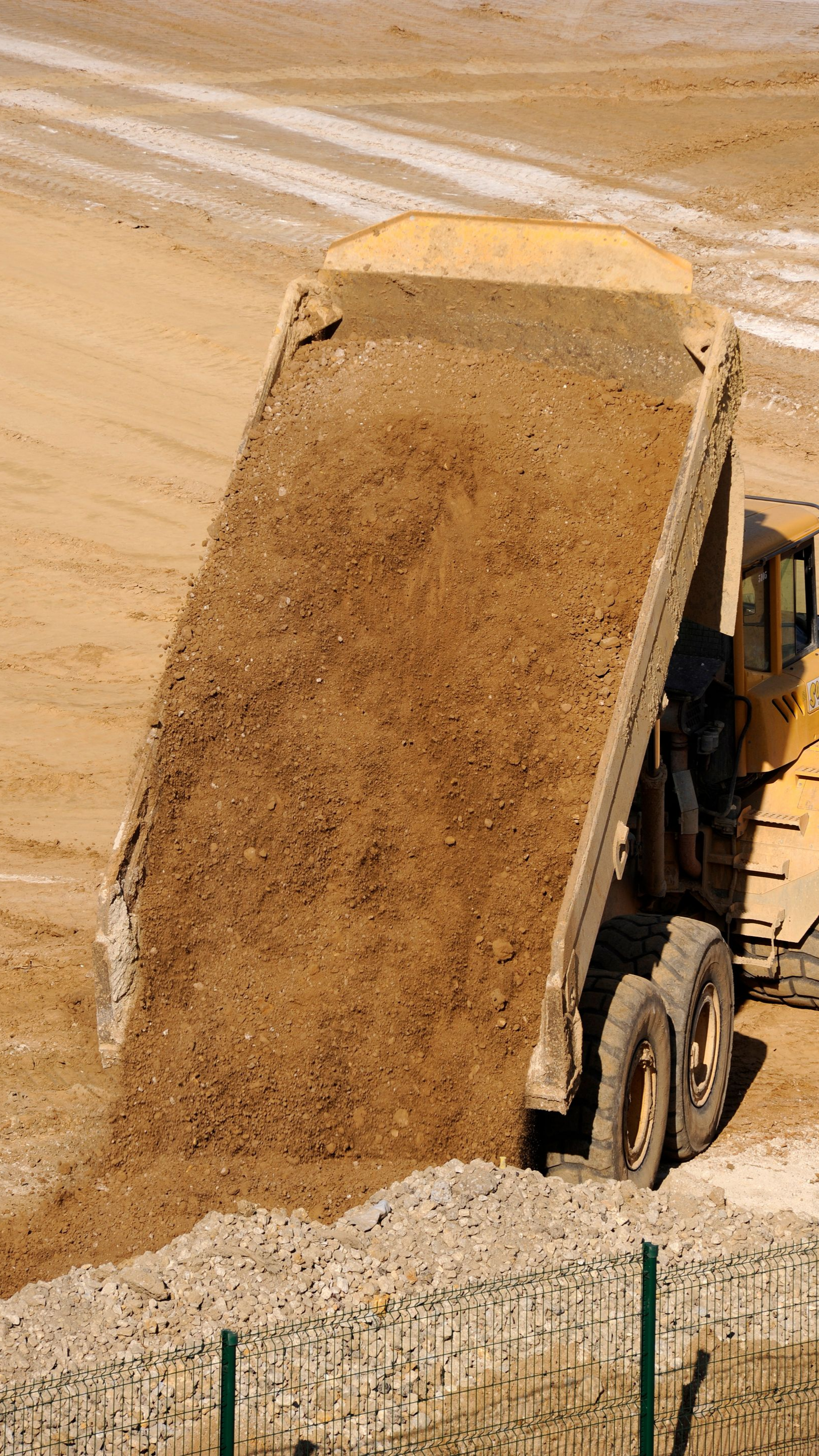 Camion-benne déchargeant de la terre sur un chantier de construction.