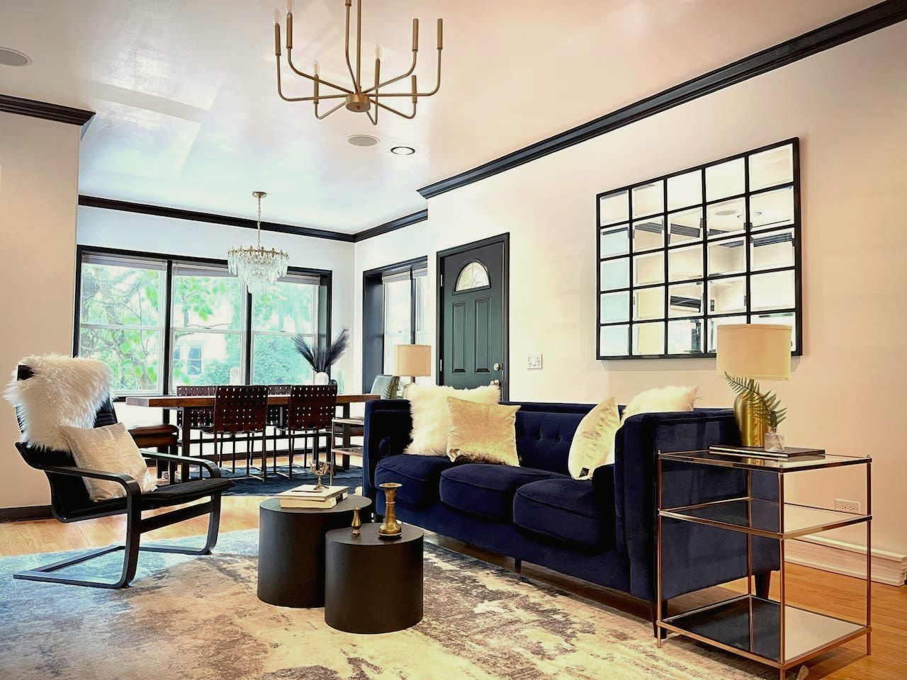 A living room with a blue couch , chairs , tables and a mirror.