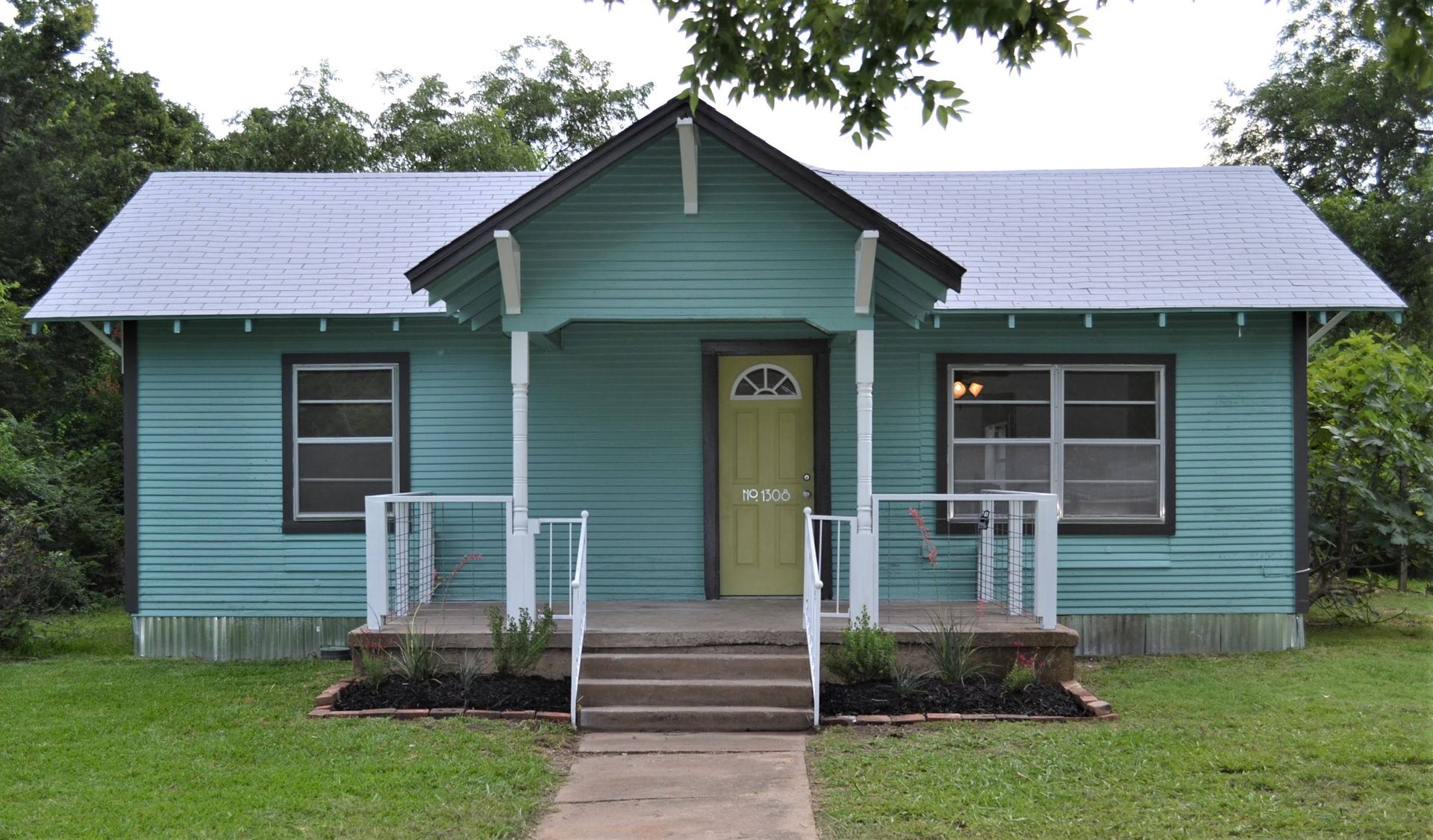 A small blue house with a porch and stairs