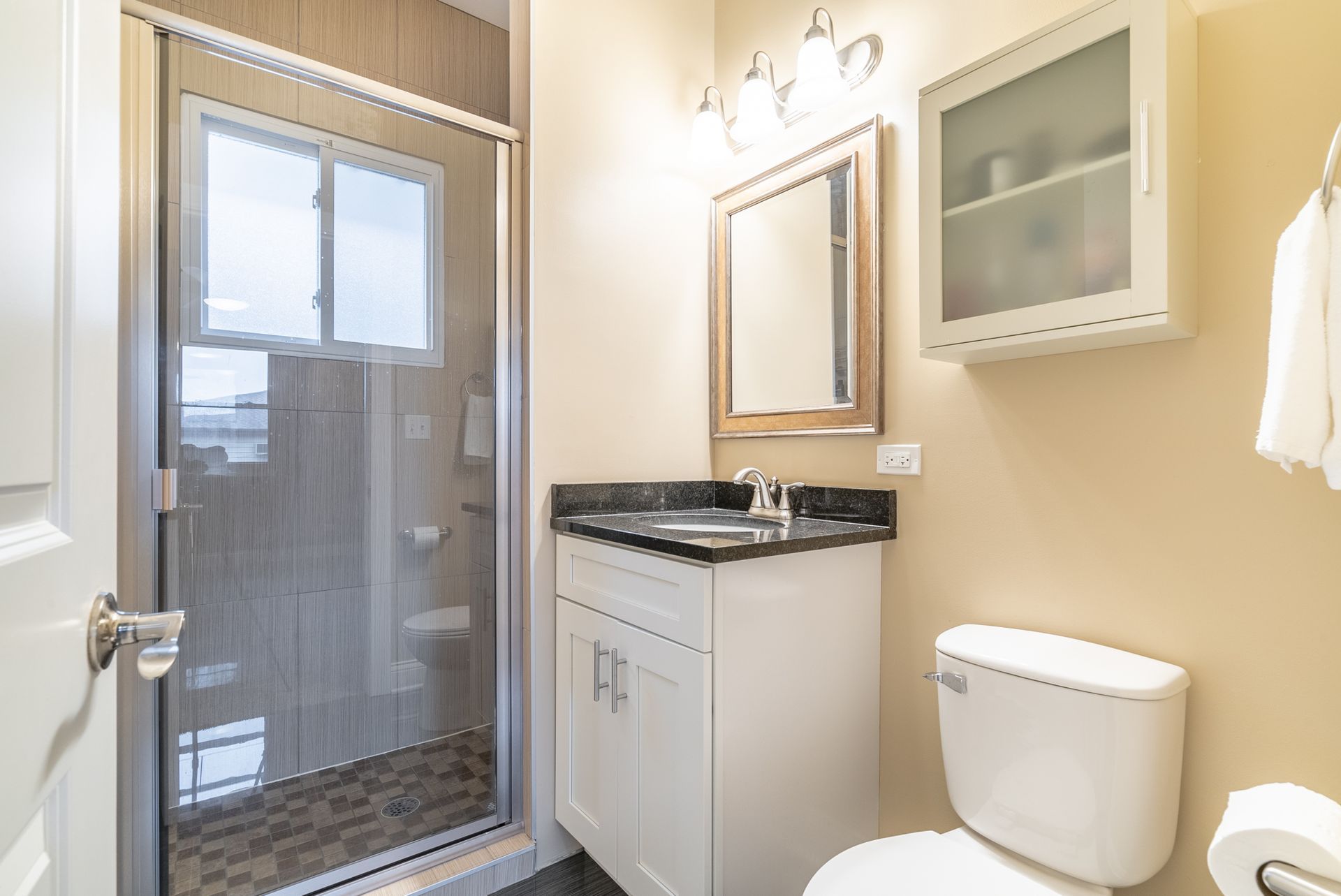 A bathroom with a toilet , sink , mirror and shower.